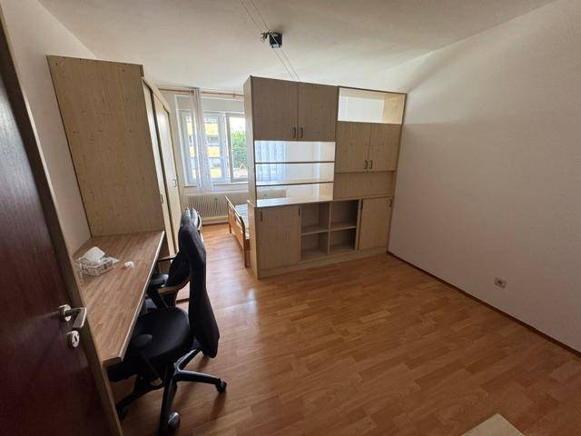 Helles Schlafzimmer mit Laminatboden, Schreibtisch und Einbauschränken.