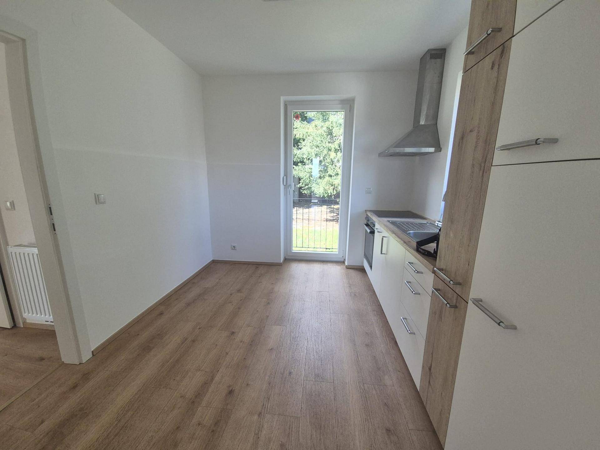 Funktionale Küche mit ausreichend Platz und direktem Zugang zu einem Außenbereich durch eine Fenstertür.
