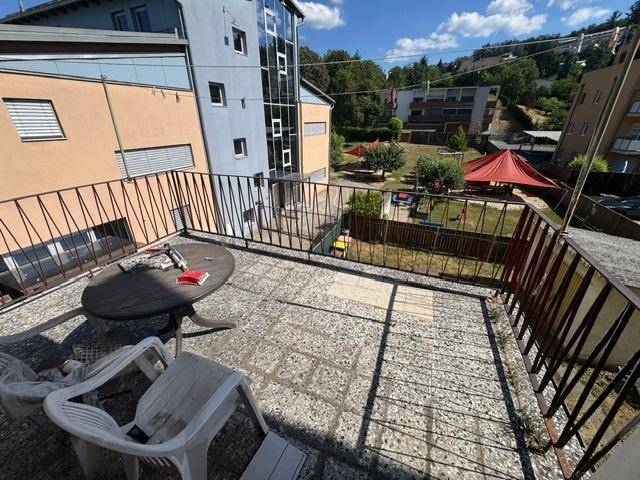 Große geflieste Terrasse mit Sitzgelegenheiten und Blick auf den Gartenbereich und Nachbargebäude.
