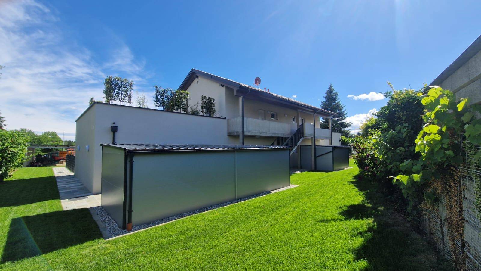 Gepflegter Gartenbereich mit Rasenfläche und einem modernen Nebengebäude im Freien.