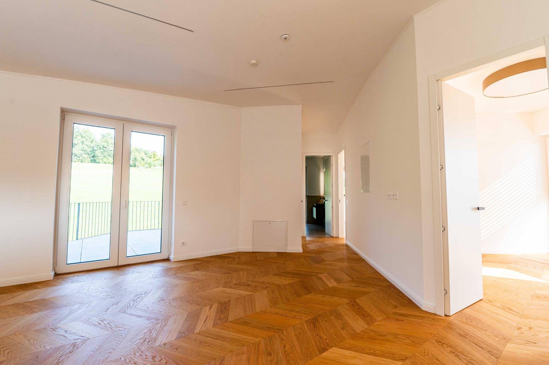 Lichtdurchfluteter Wohnbereich mit Holzboden und Zugang zu weiteren Räumen.