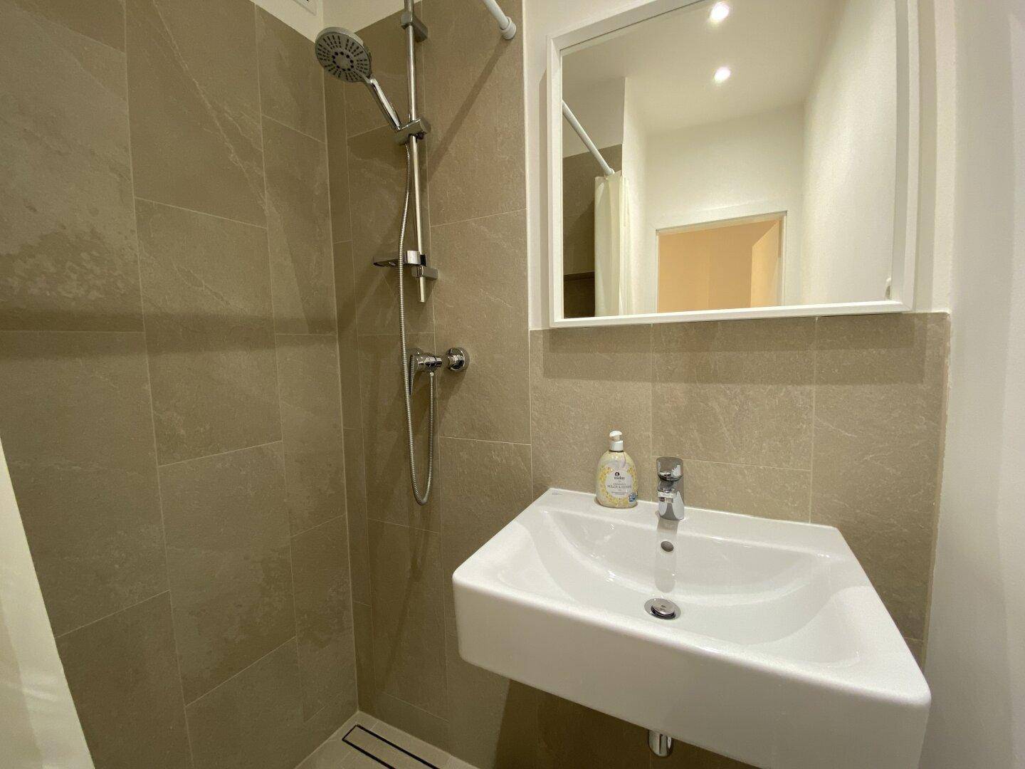 Detailansicht des Badezimmers mit modernem Waschbecken und Duscharmatur.