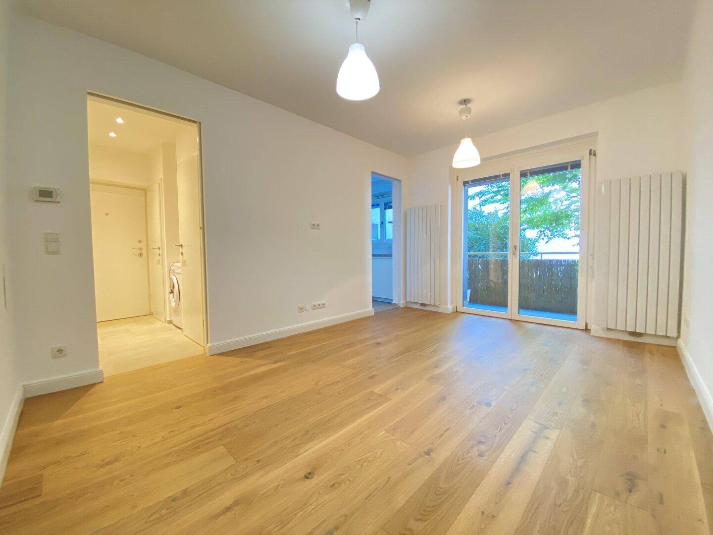 Helles Wohnzimmer mit neuem Eichenparkettboden und Zugang zu einem kleinen Balkon.