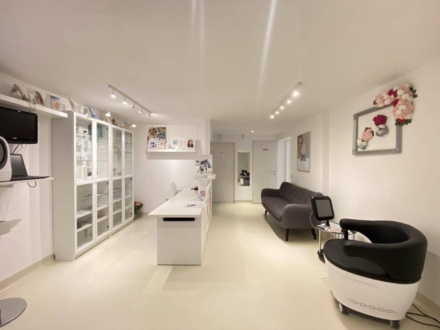 Heller Empfangsbereich mit moderner Einrichtung, bequemen Sitzgelegenheiten und Produktpräsentationsvitrinen.