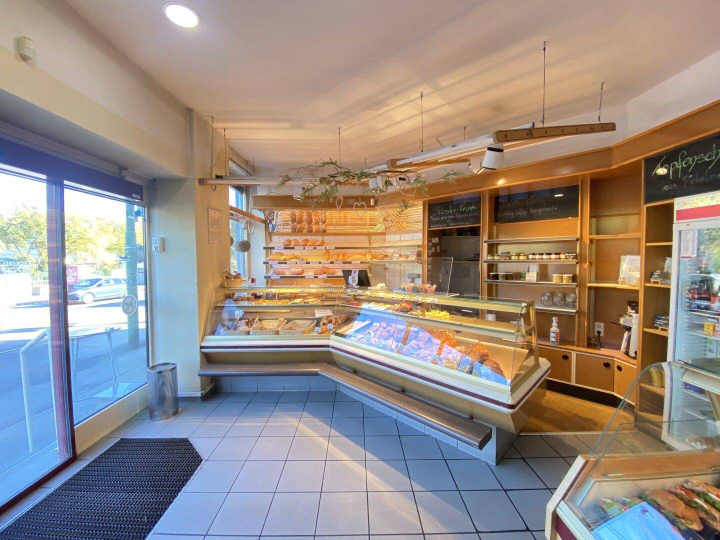 Heller Verkaufsraum einer Bäckerei mit umfangreicher Auslage und Fliesenboden.