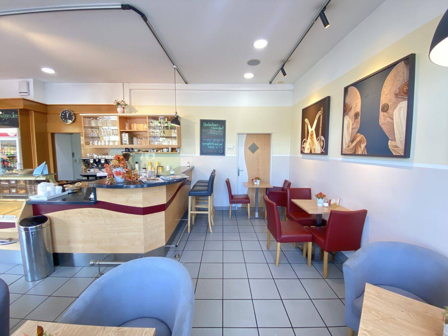 Sitzbereich und Theke im Café mit roten Stühlen und Wanddekoration.