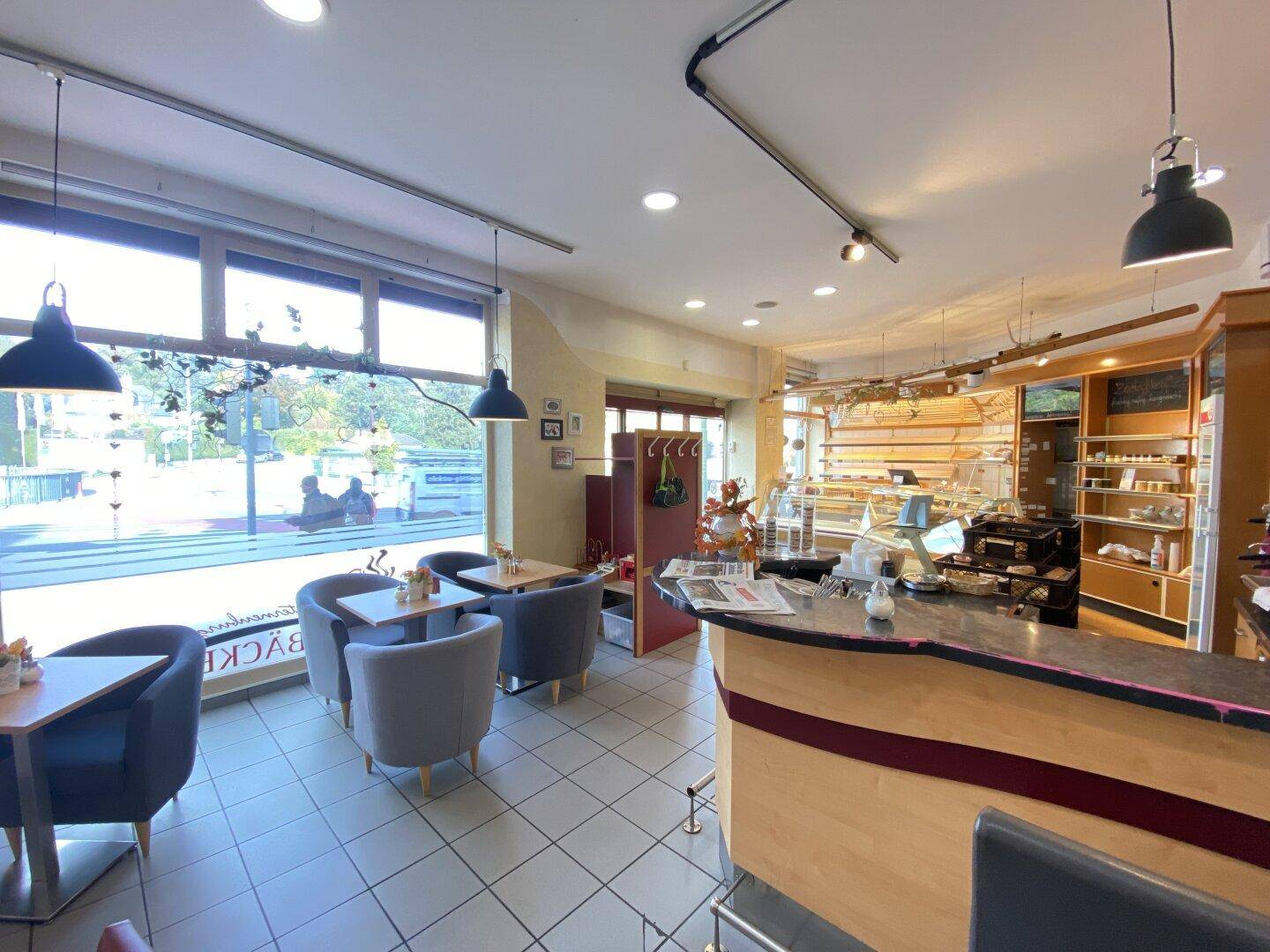 Gemütlicher Café-Sitzbereich mit bequemen Stühlen, Tischen und Blick auf die Straße.