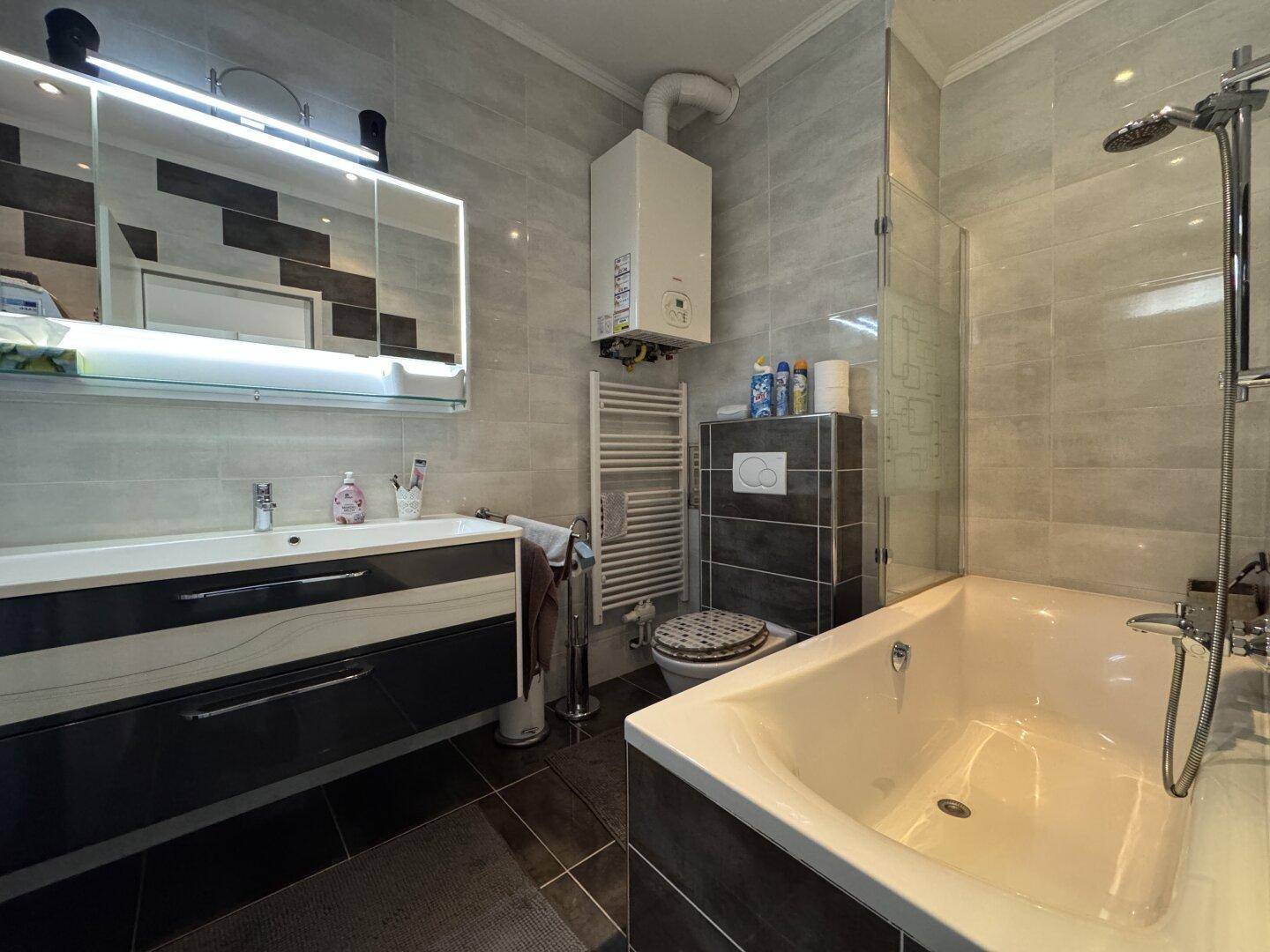 Modernes Badezimmer mit Badewanne, Dusche, Waschtisch und Heizkörper.