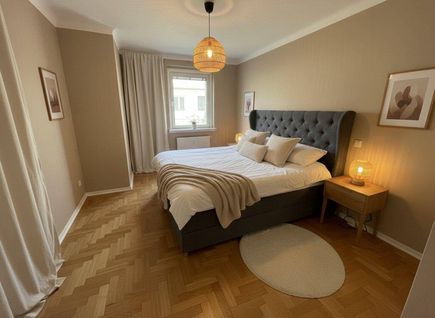 Gemütliches Schlafzimmer mit Fischgrätparkett, großem Doppelbett und natürlichem Lichteinfall.