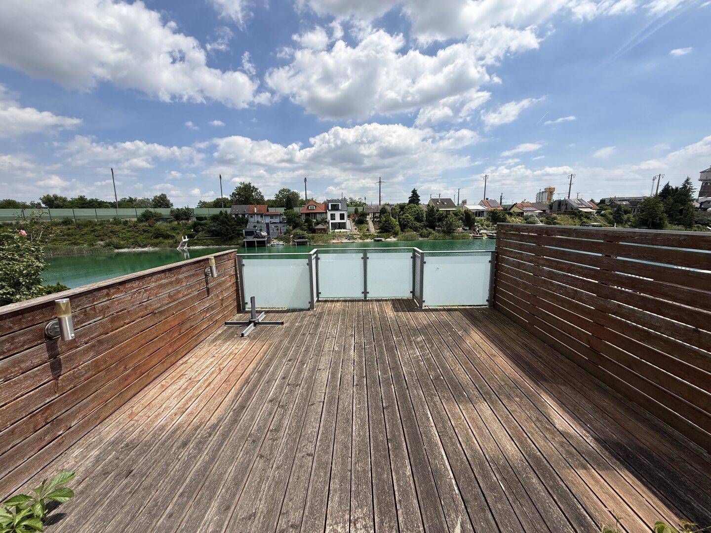 Große Holzterrasse mit Holzzaun und weitem Blick über das Wasser.