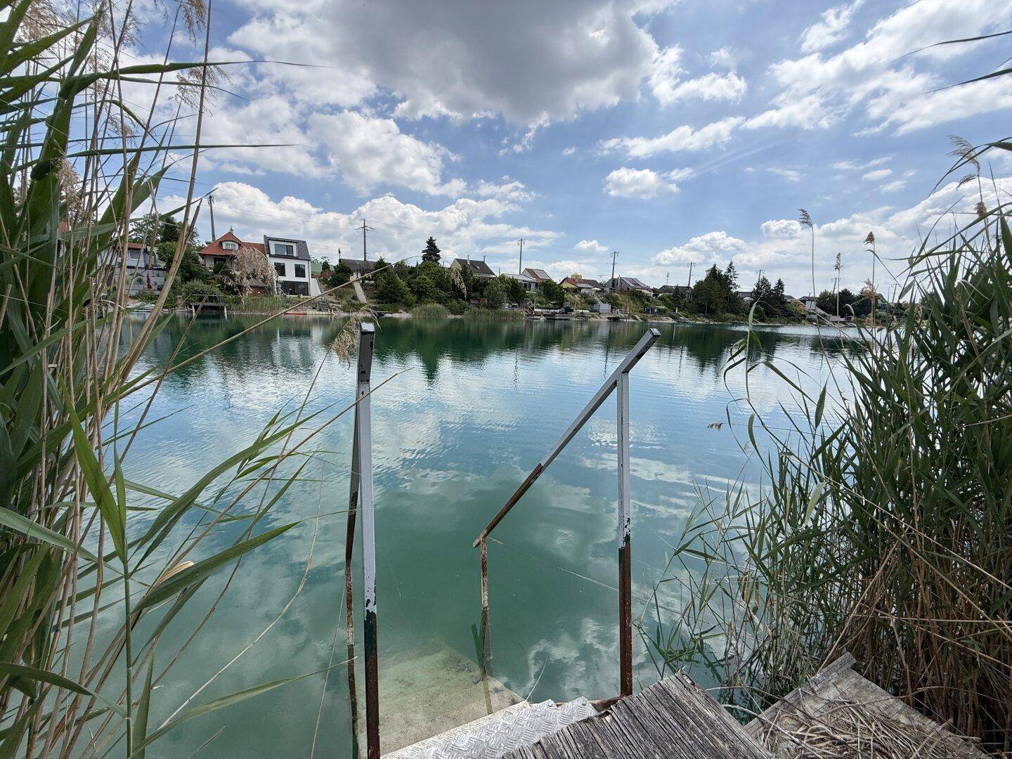 Treppe führt direkt ins klare Wasser des Sees, umgeben von üppigem Schilf.