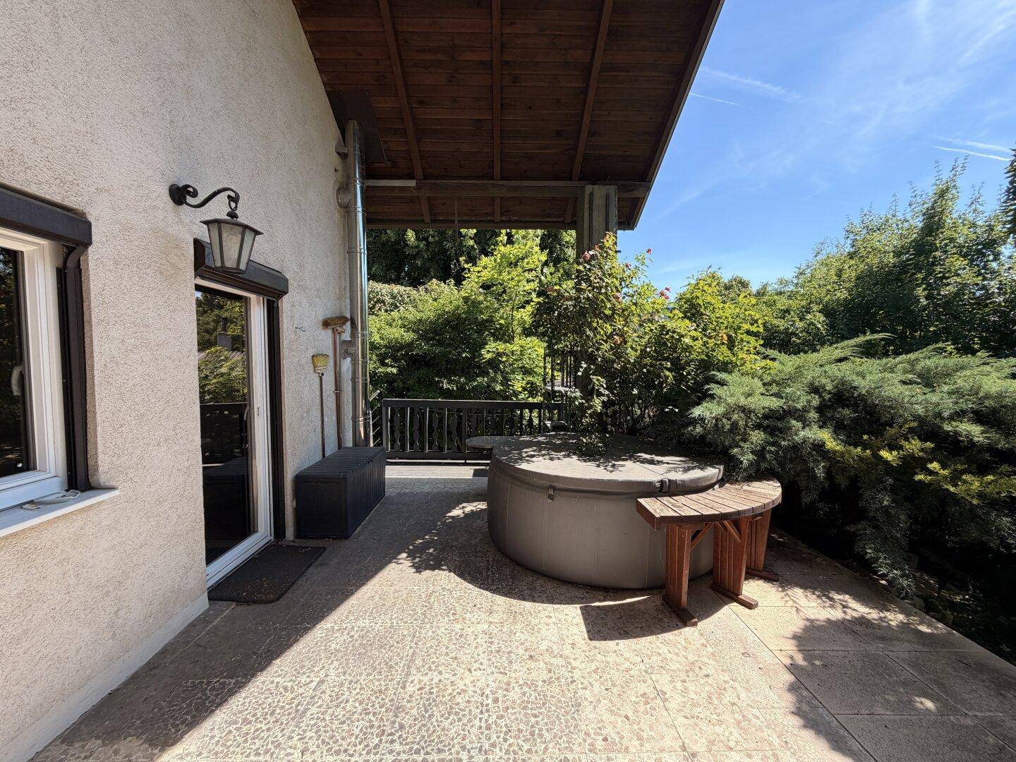 Überdachte Terrasse mit einem Whirlpool und Blick ins Grüne, ideal zum Entspannen im Freien.