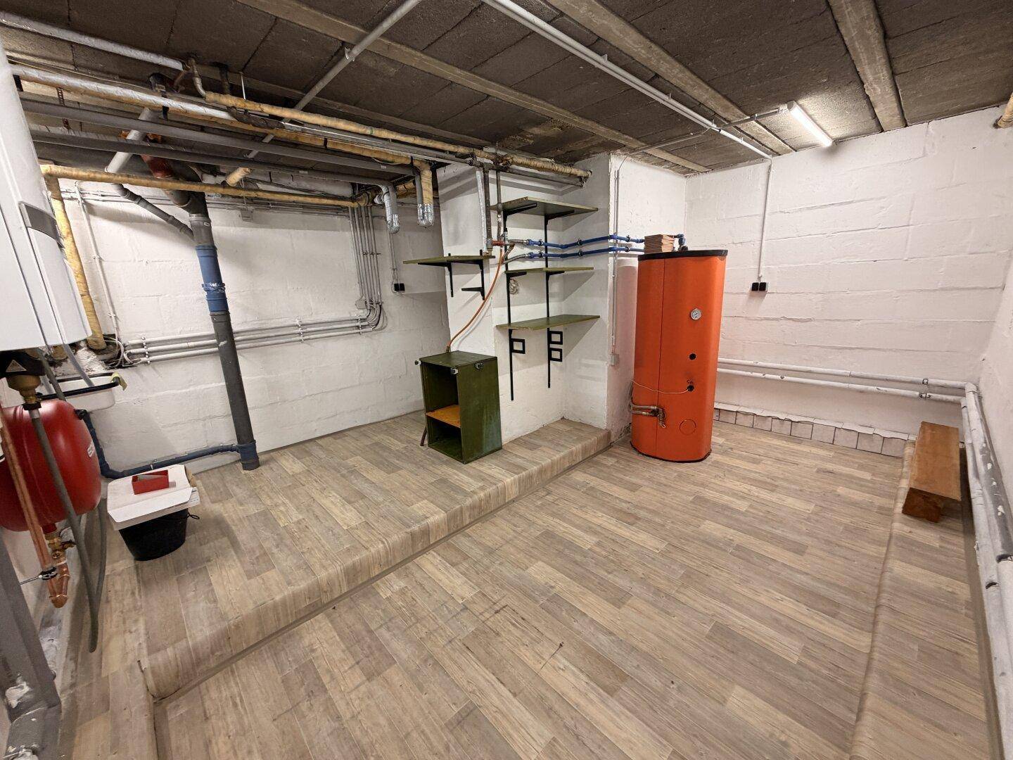 Heizungsraum im Keller mit Warmwasserspeicher und Installationen, gut zugänglich.