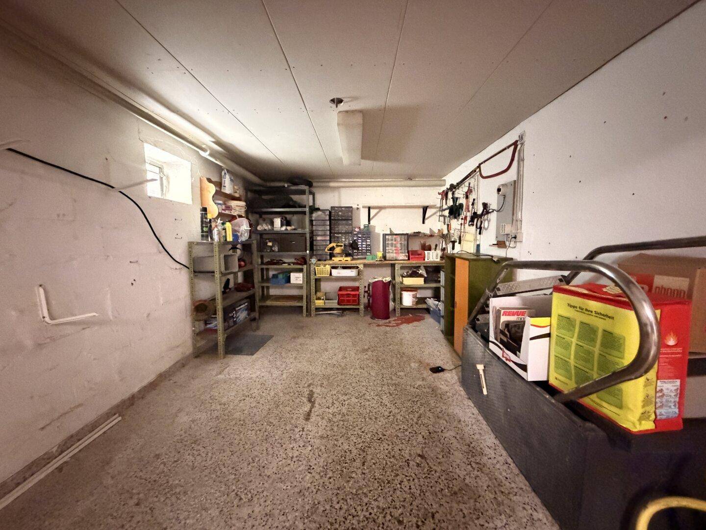 Werkstatt im Keller mit Regalen und Arbeitsflächen, ideal für Heimwerker und Lagerung.