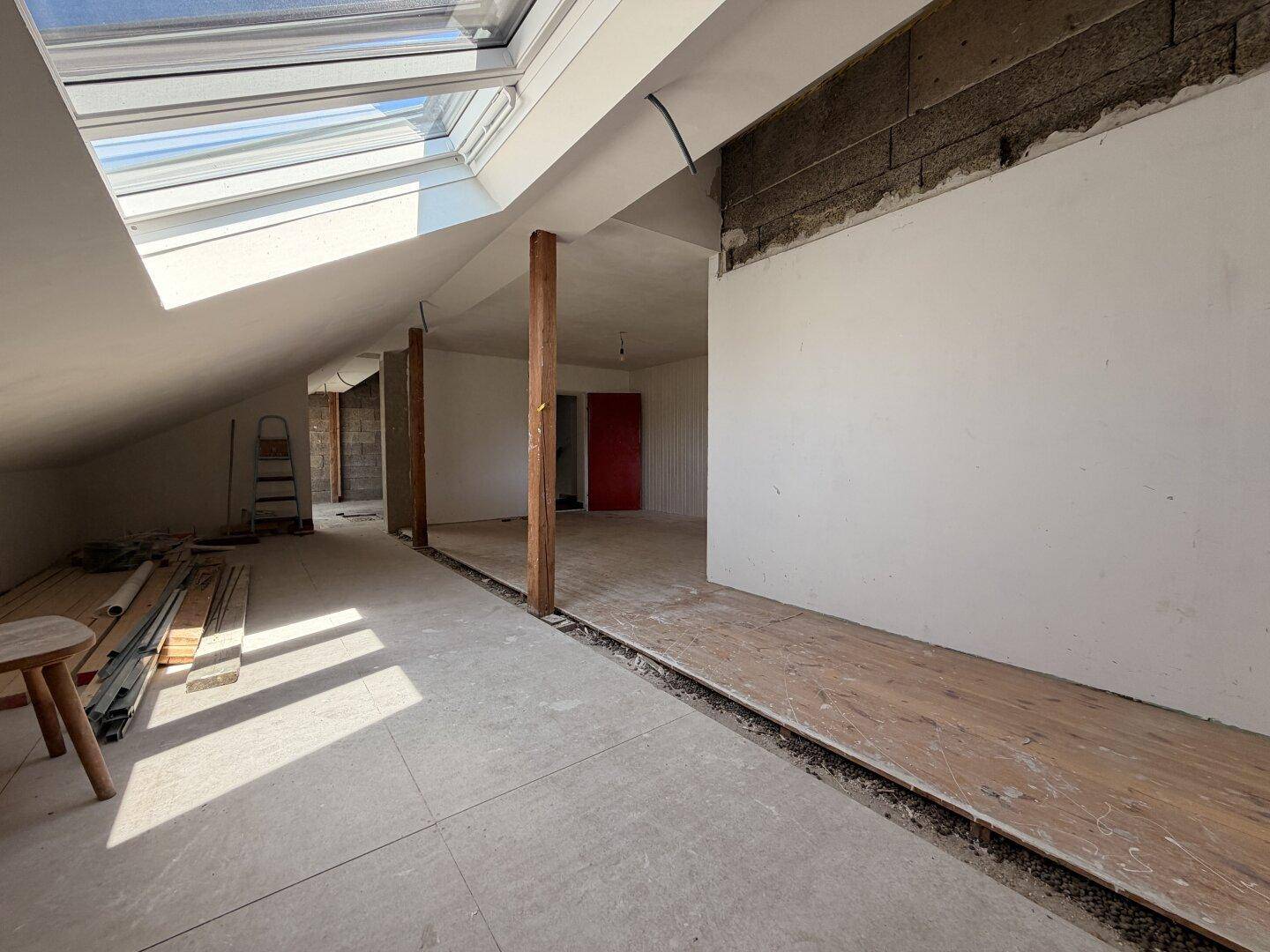 Weiterer Blick in den Dachboden mit Dachfenster und teilweise verlegtem Bodenbelag.