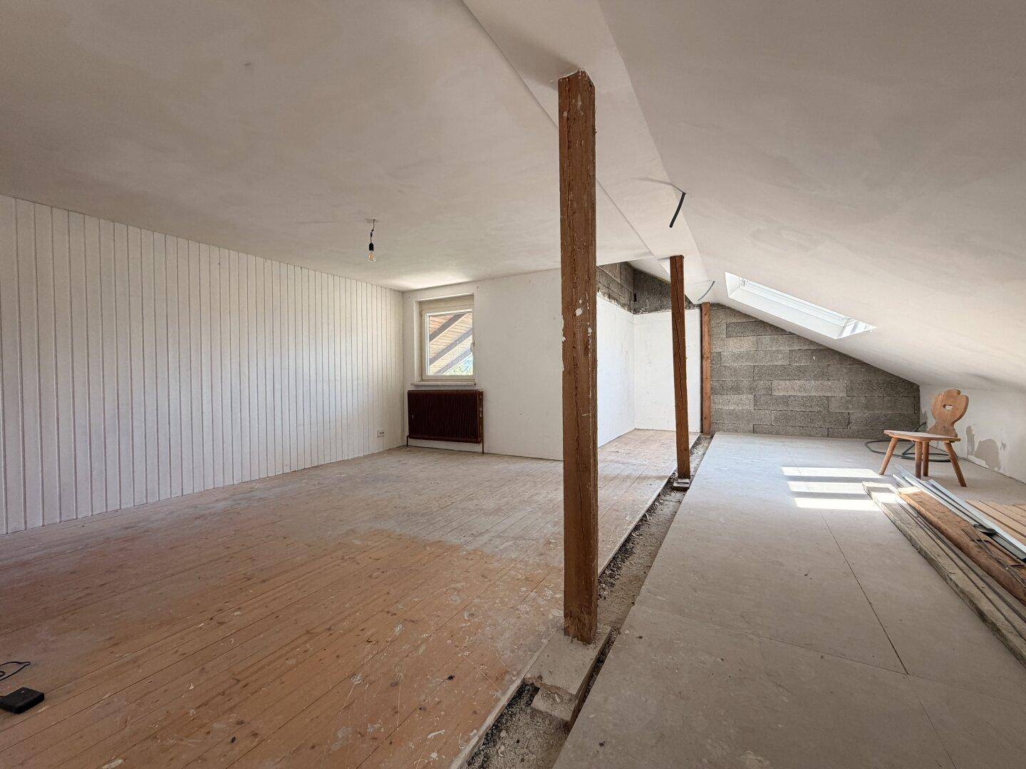 Großer Dachbodenraum mit Holzboden und Dachschrägen, bereit für den weiteren Ausbau.