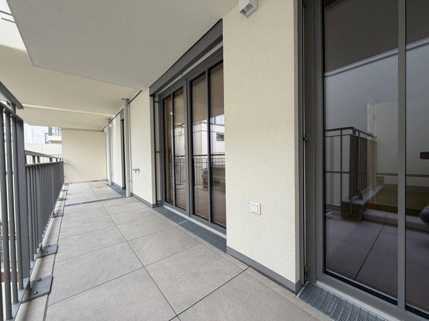 Geräumiger Balkon mit Fliesenboden und Blick auf die Umgebung.