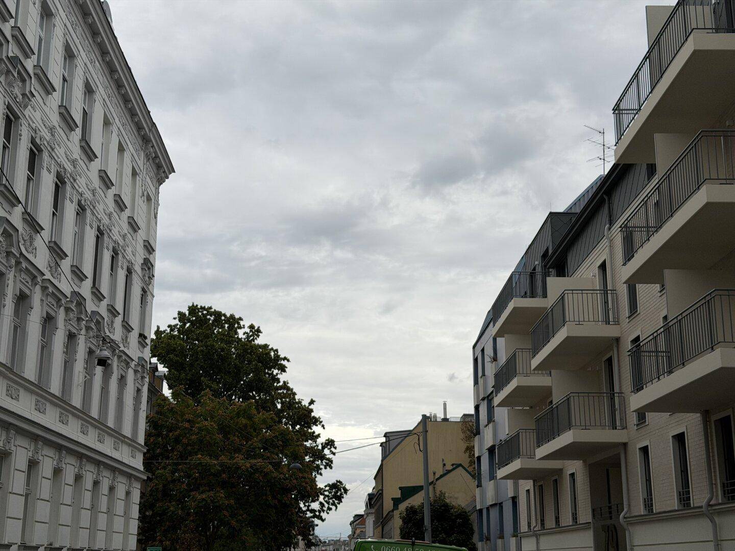 Stadtansicht mit moderner Architektur und einem historischen Gebäude unter bewölktem Himmel.