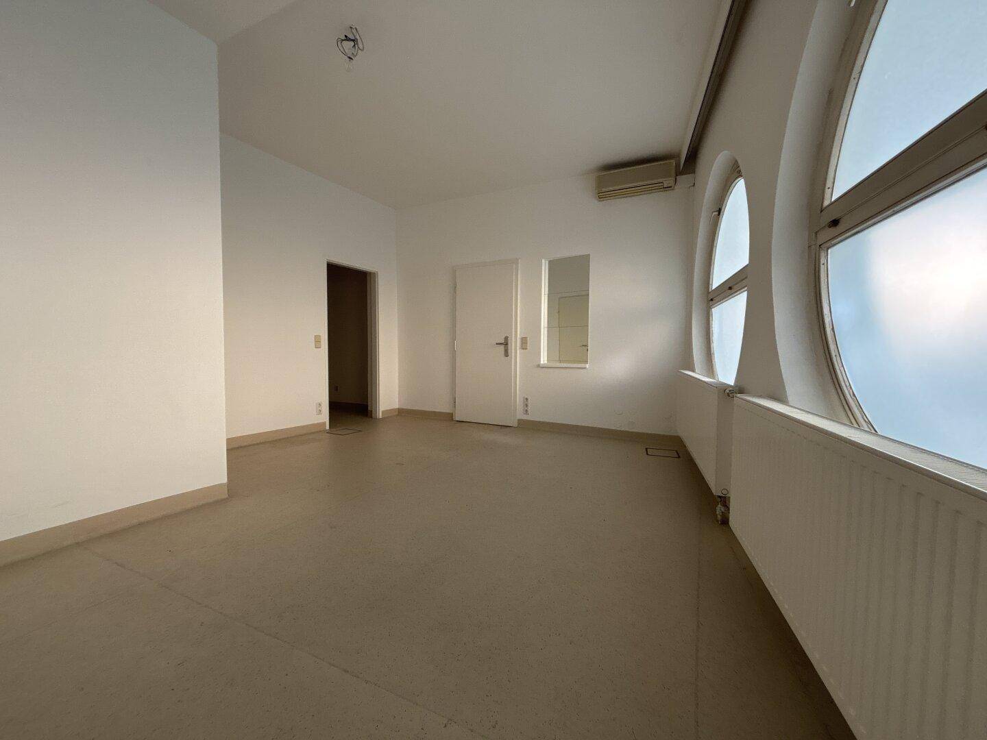 Geräumiger Raum mit runden Fenstern, Klimaanlage und Zugang zu weiteren Bereichen.
