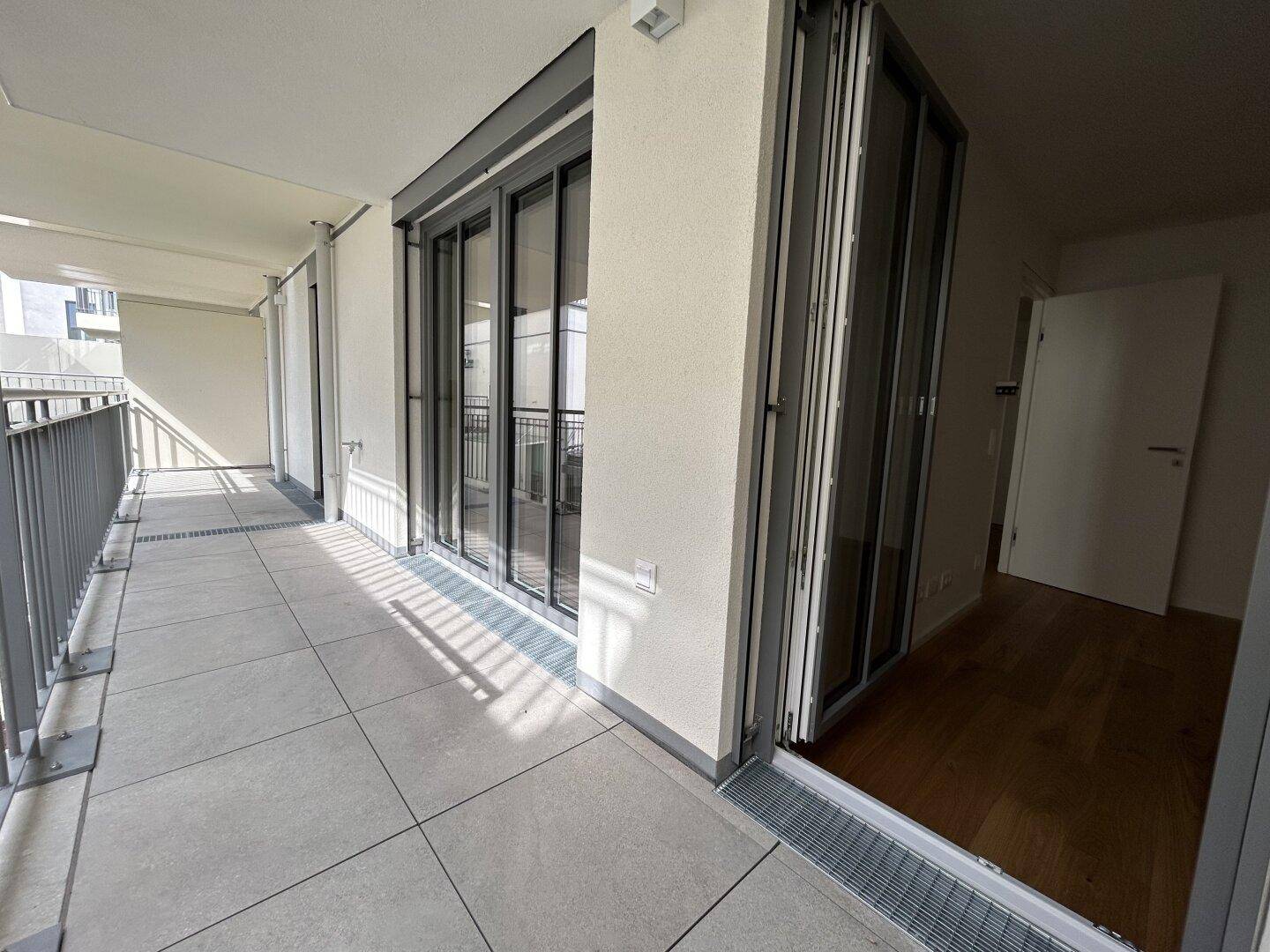 Langer, gefliester Balkon mit moderner Verglasung und direktem Zugang zu den Innenräumen.