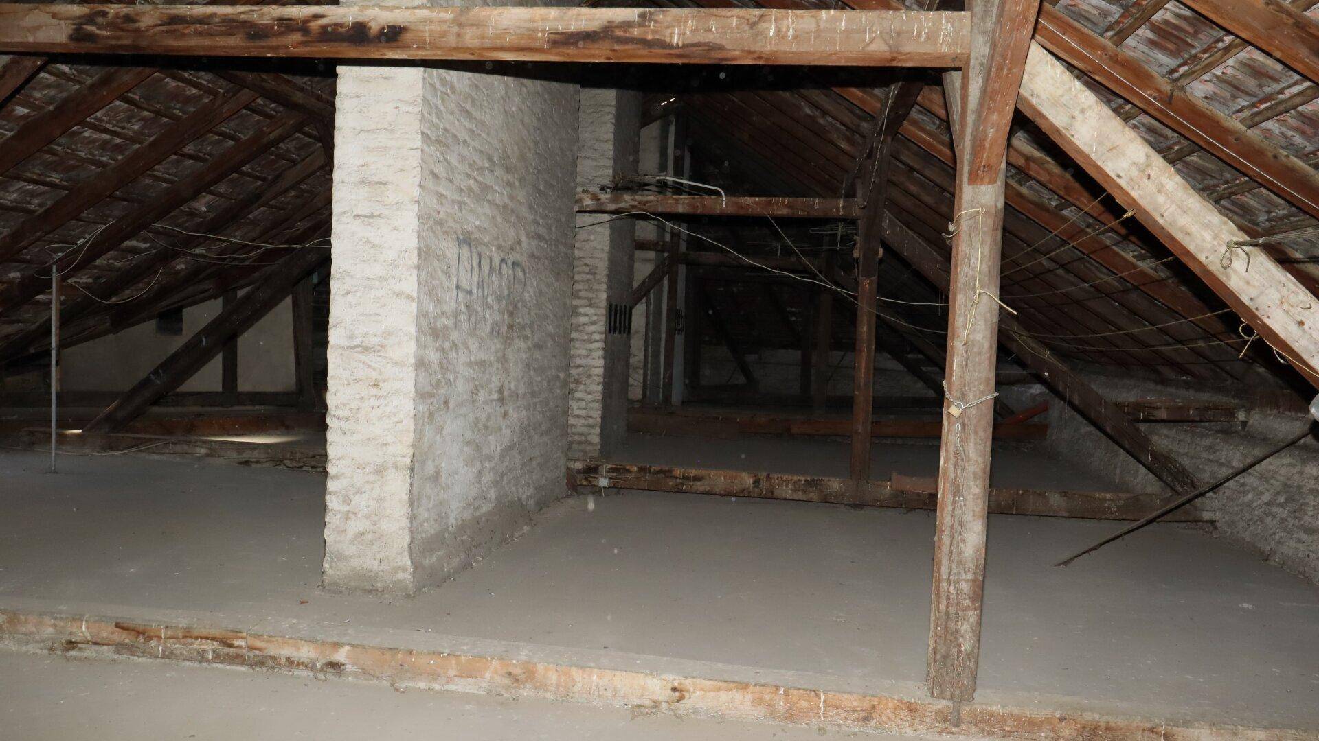 Unausgebauter Dachboden mit sichtbaren Holzbalken und Ziegeln, bereit für den Ausbau.