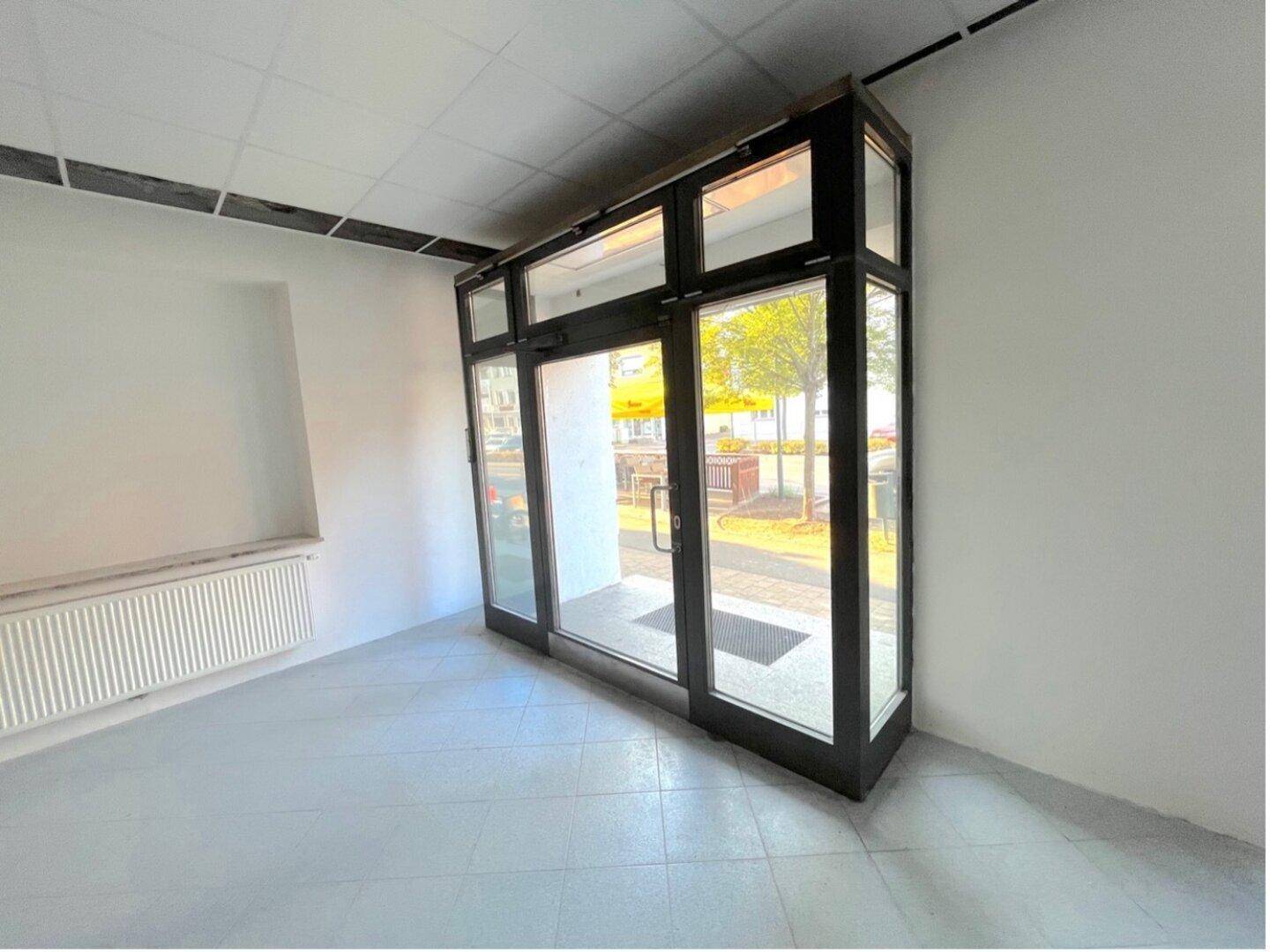 Eingangsbereich einer Gewerbefläche mit Glasfront und Heizkörper.