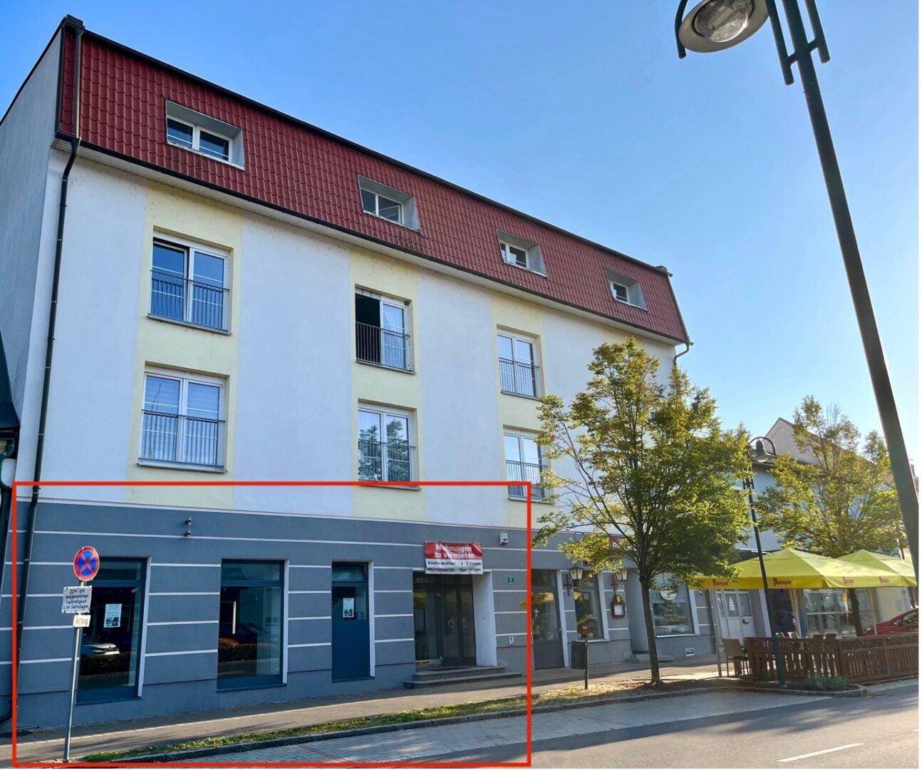 Fassade eines Gebäudes mit Erdgeschoss-Gewerbeflächen und oberen Wohnetagen, rot umrandet.