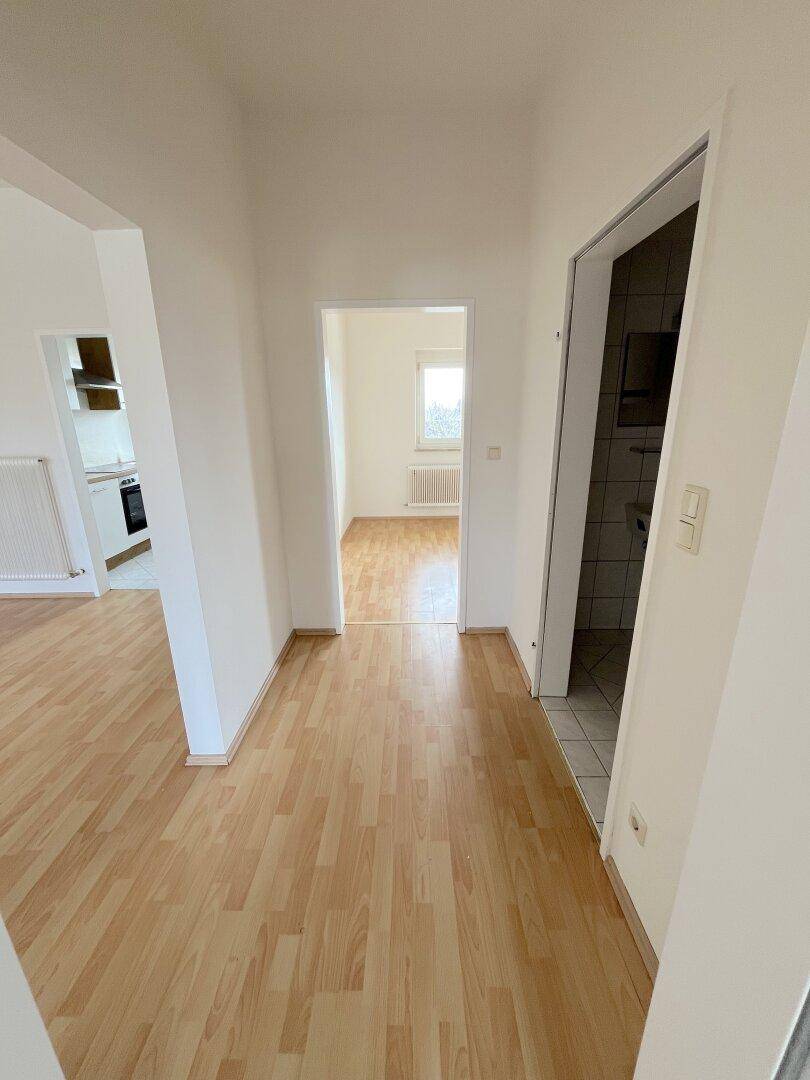 Heller Flur mit Laminatboden, der zu verschiedenen Räumen mit Fliesen- und Laminatböden führt.