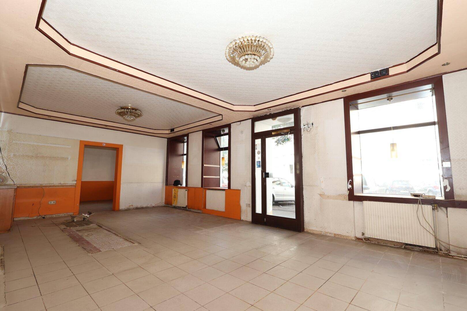 Großer leerer Raum mit dekorativer Decke und Fliesenboden, bereit für Renovierung und Neugestaltung.