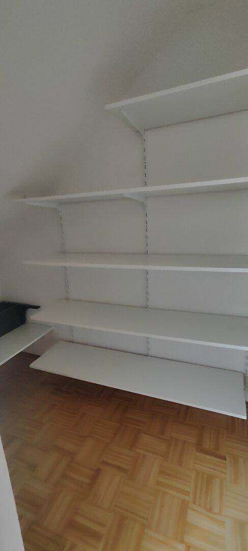 Innenansicht eines Abstellraums mit vielen weißen Regalböden für Organisation.