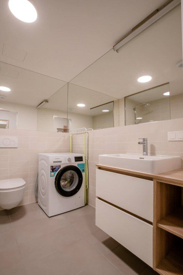 Helles Badezimmer mit Waschmaschine, modernem Waschtisch und Wand-WC.