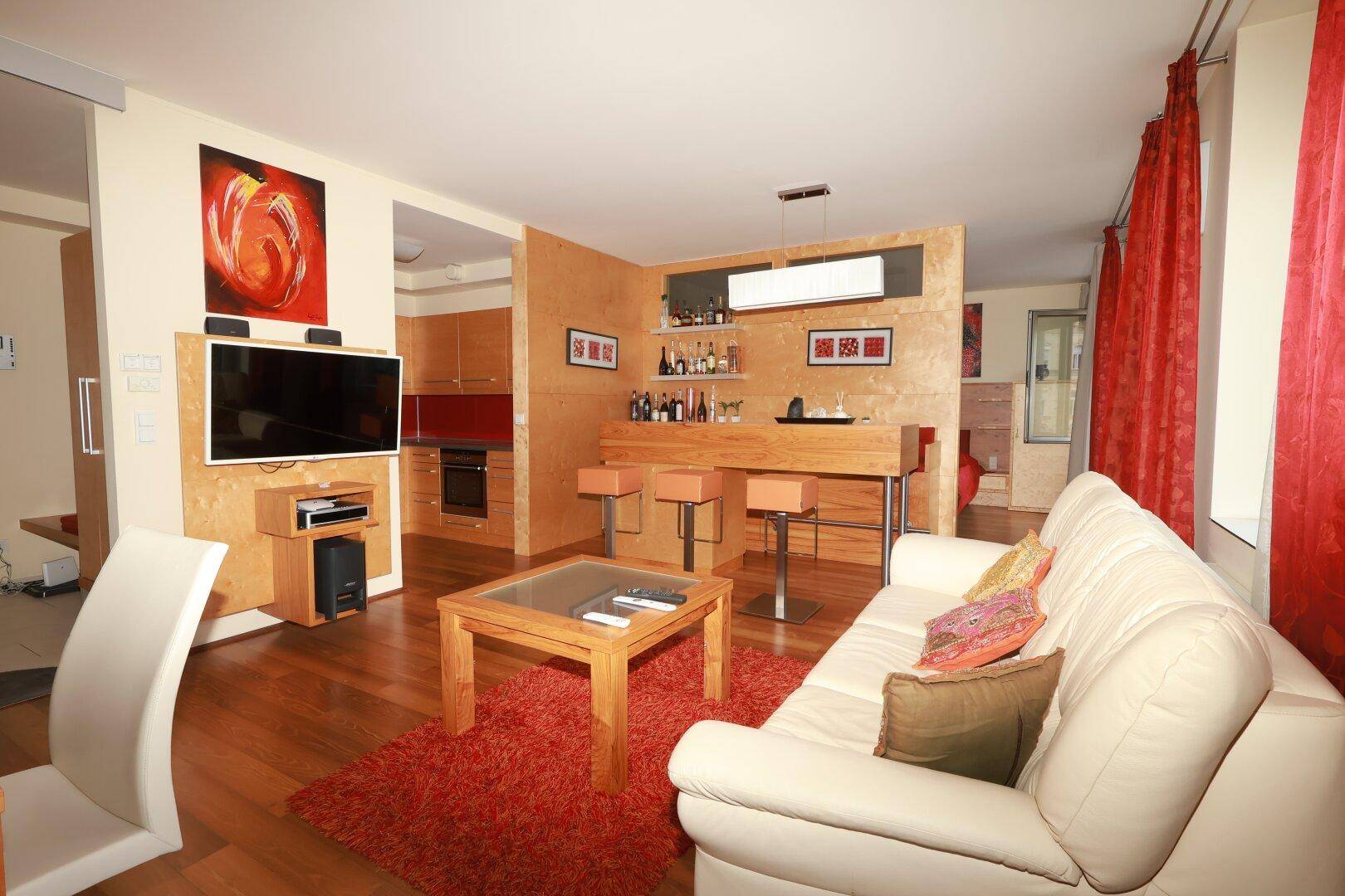 Moderner Wohnbereich mit Fernseher, Bar und Blick auf die angrenzende Küche.