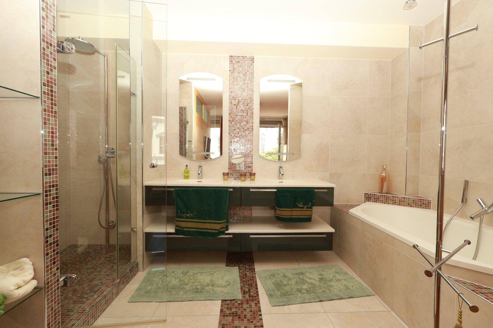 Modernes Badezimmer mit Doppelwaschbecken, Dusche und Badewanne sowie hellen Fliesen.