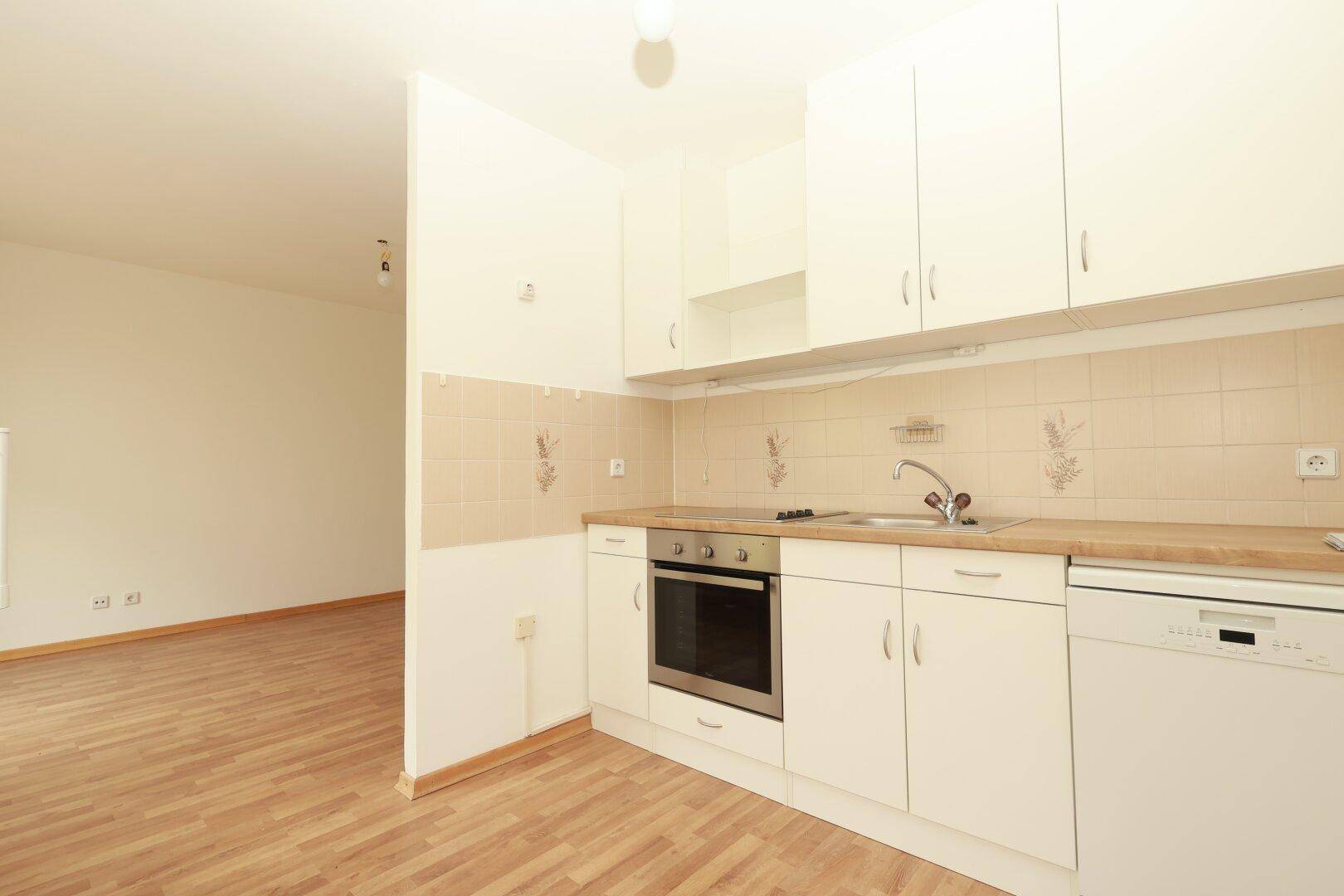 Funktionale Einbauküche mit weißen Schränken, Holz-Arbeitsplatte und integrierten Geräten.