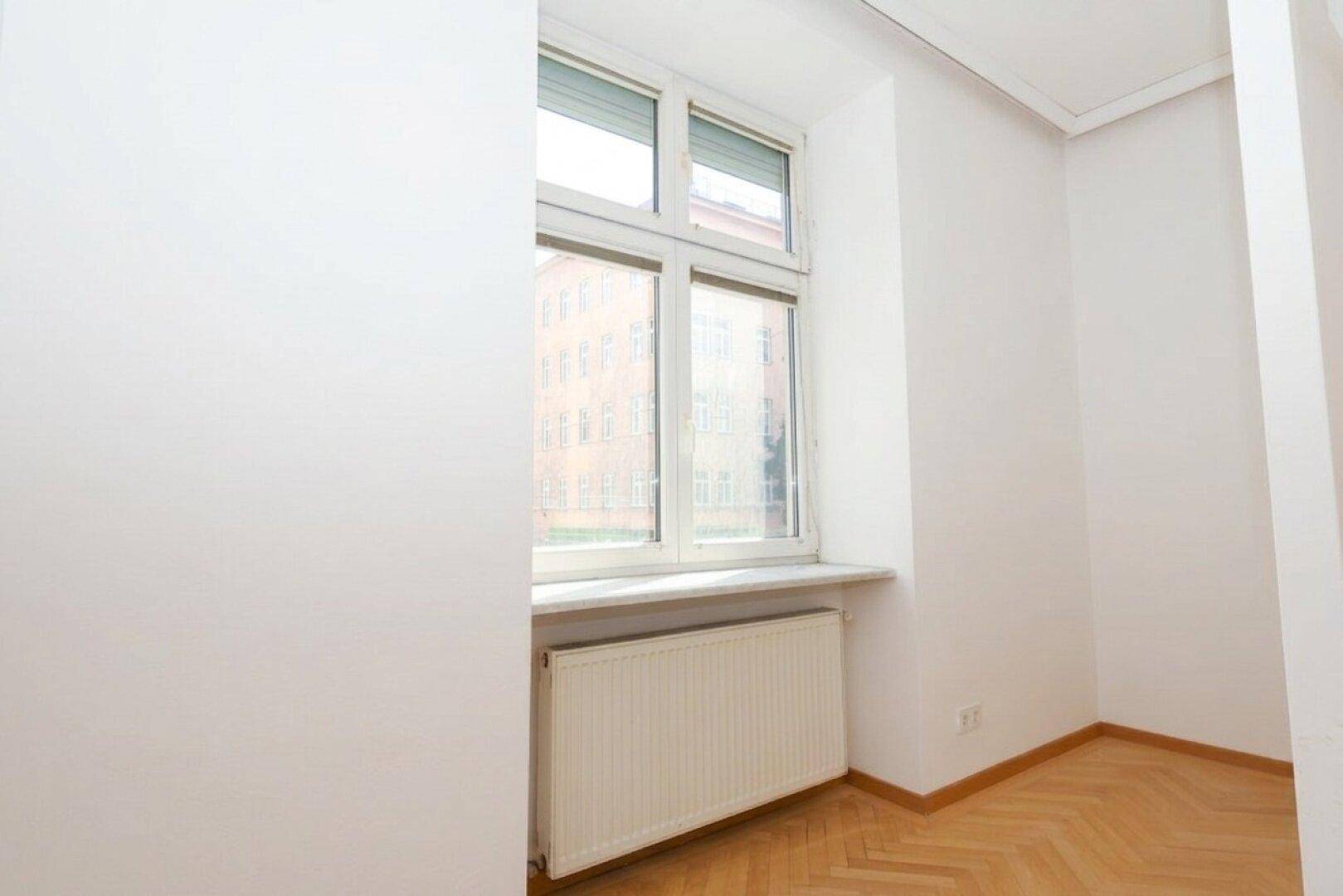Detailansicht eines Fensters mit Rollladen und Heizkörper in einem hellen Raum.