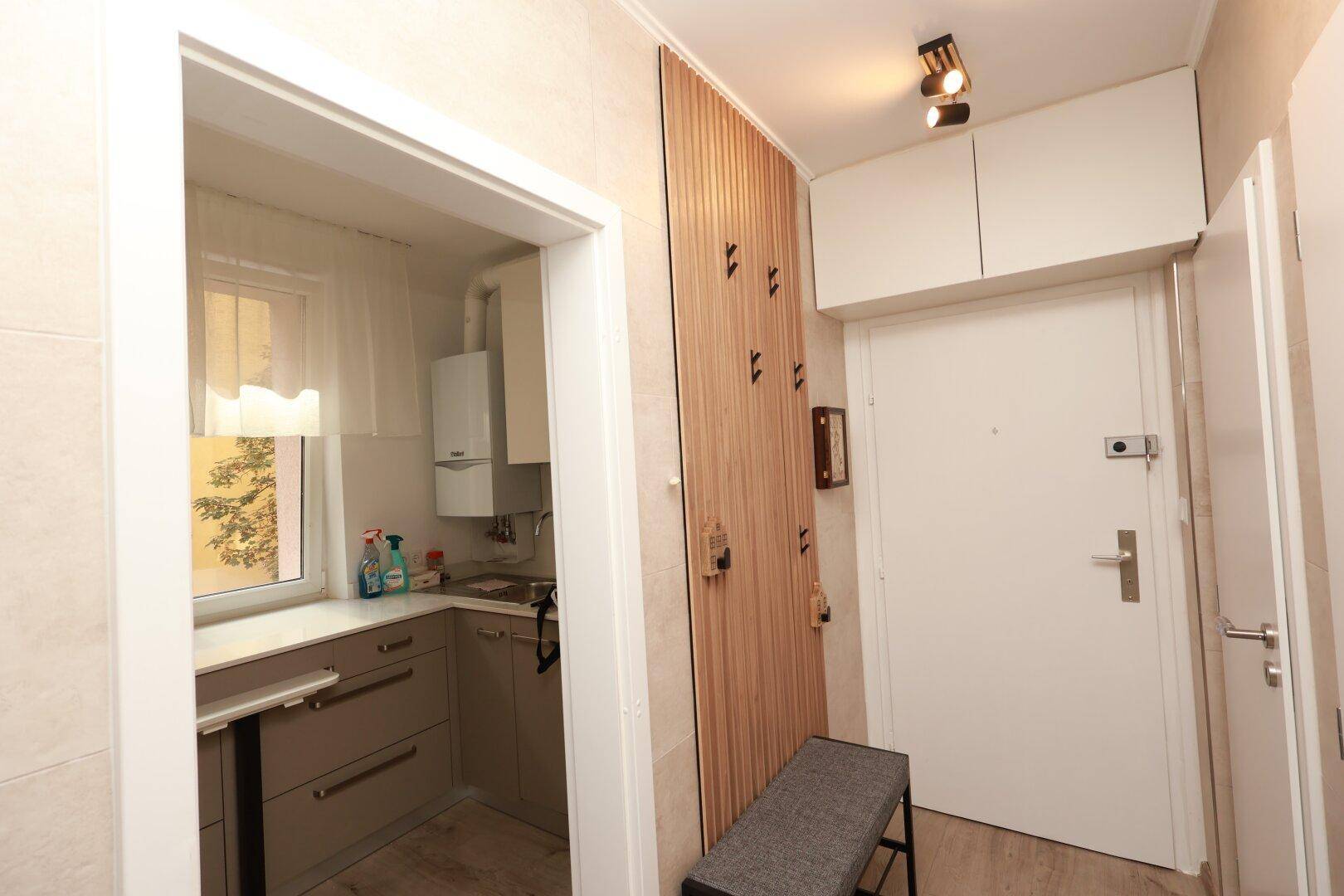 Heller Flur mit Garderobe und direktem Zugang zur funktionalen Küche.