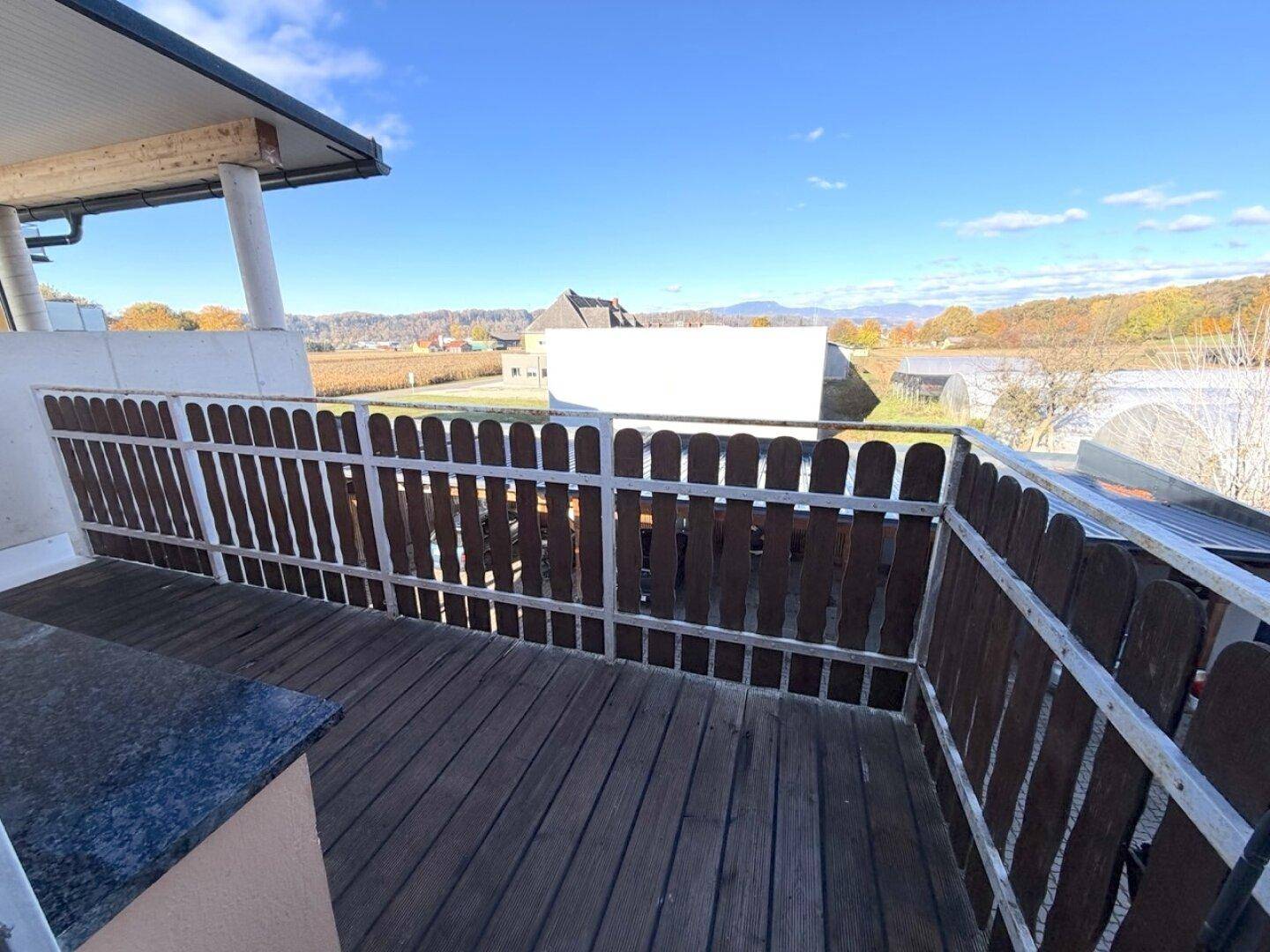 Geräumiger Balkon mit Holzboden und weitem Blick über die Landschaft und Berge.