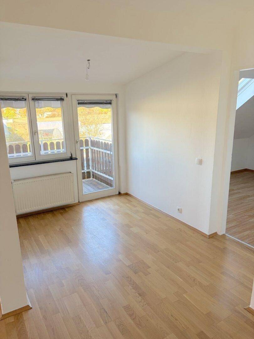 Heller Raum mit Parkettboden, großem Fenster und direktem Zugang zu einem Balkon.