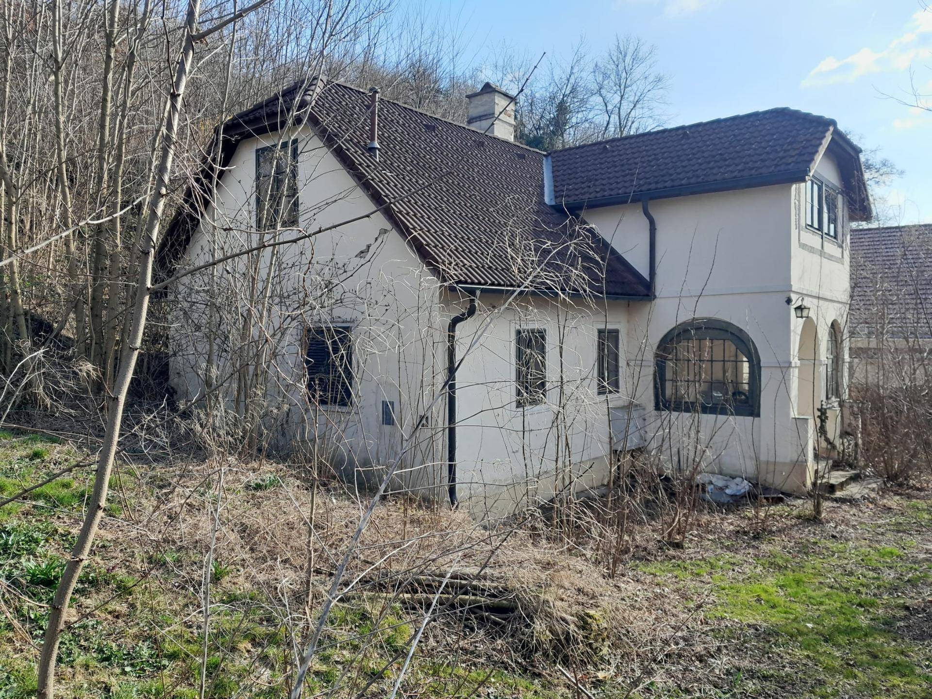 Gesamtansicht eines älteren Wohnhauses mit Satteldach und bewachsenem Grundstück in ländlicher Umgebung.