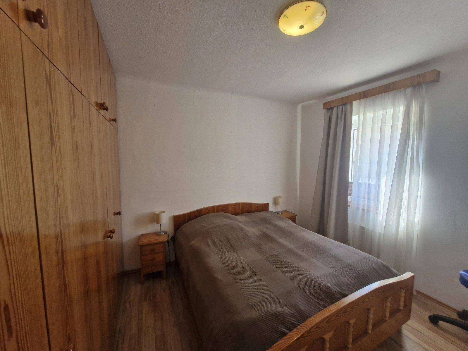Gemütliches Schlafzimmer mit Doppelbett, Holzschrank und Fenster für natürliches Licht.