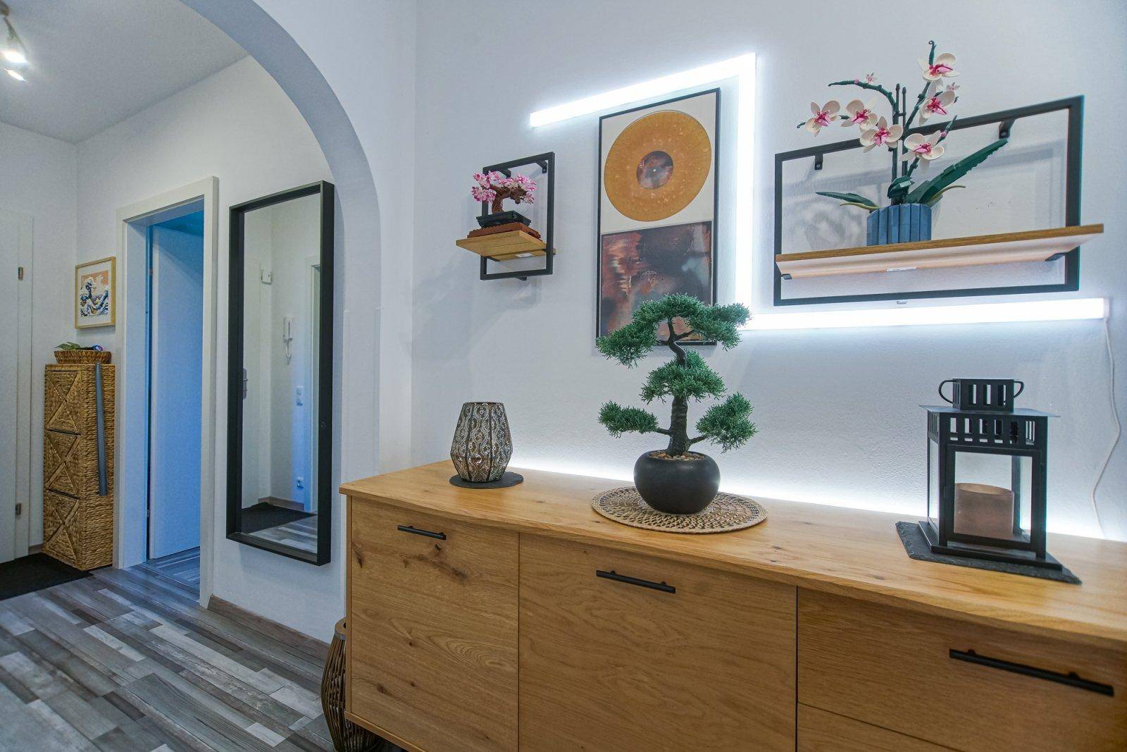 Detailansicht der Holzkommode im Flur mit stilvoller Dekoration und indirekter LED-Beleuchtung.