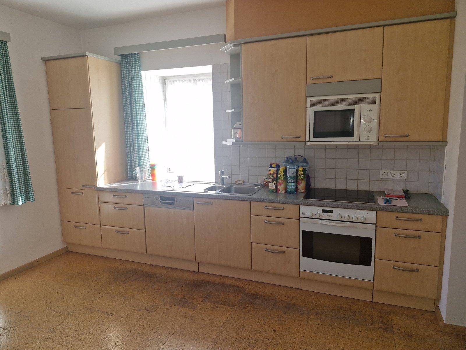 Funktionale Küche mit hellen Holzschränken, Einbaugeräten und Fenster.