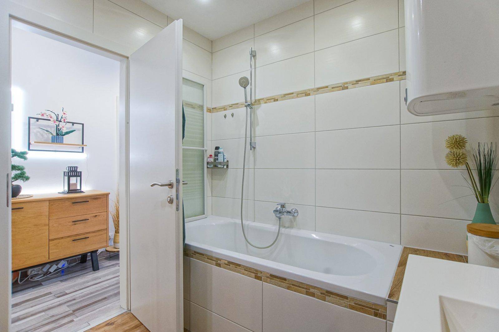 Helles Badezimmer mit Badewanne und offenem Zugang zum Flurbereich.