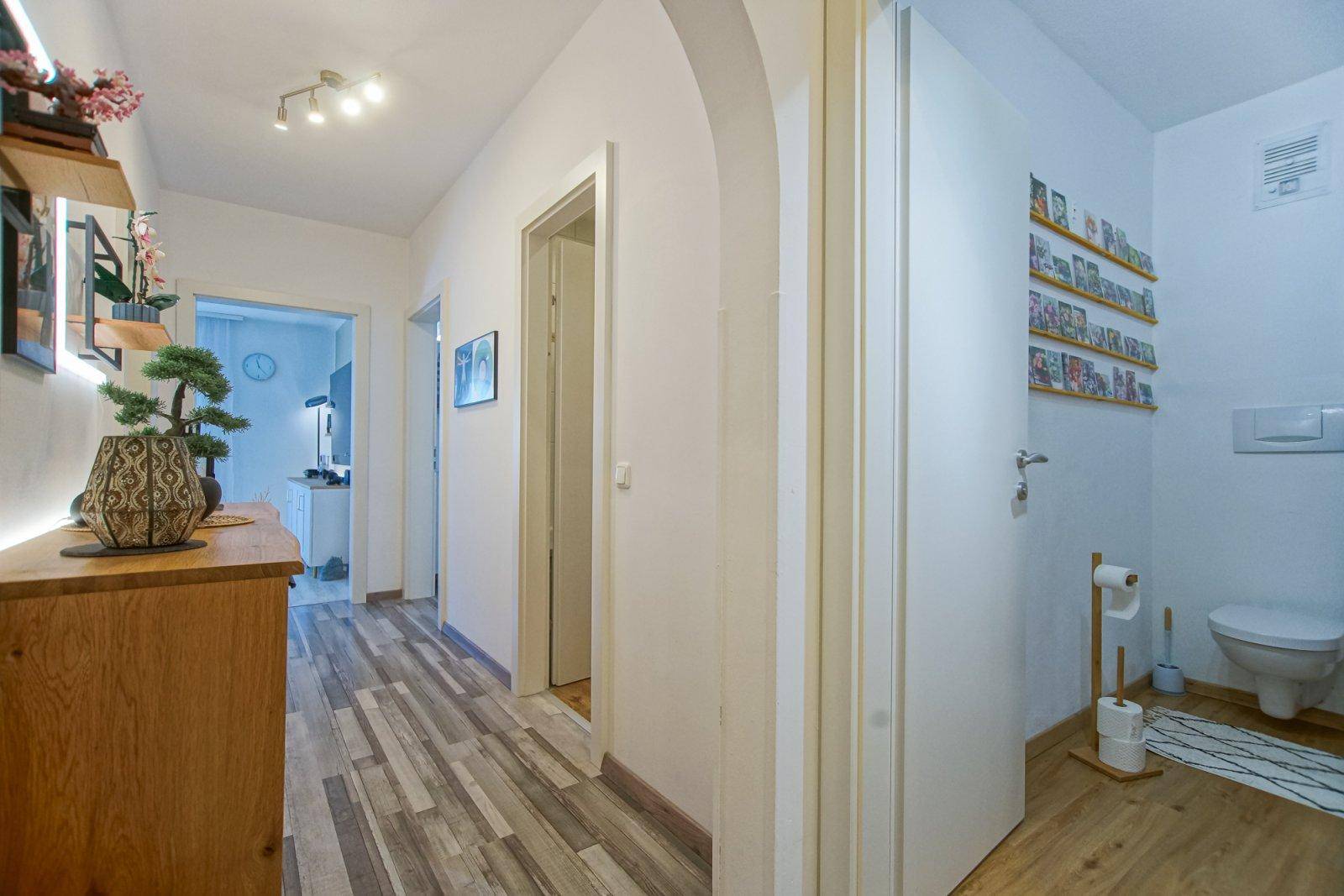 Flur mit Blick auf ein separates WC und eine moderne Holzkommode.