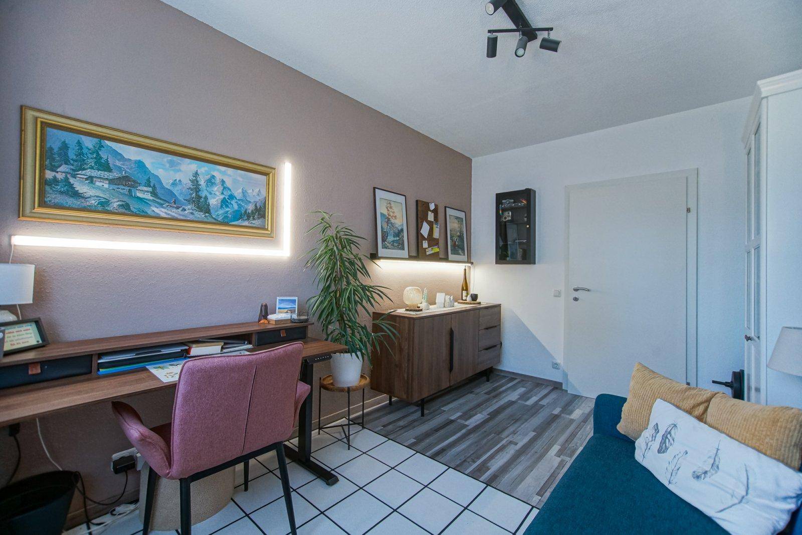 Modernes Arbeitszimmer mit Schreibtisch, Holzkommode und einer blauen Couch.