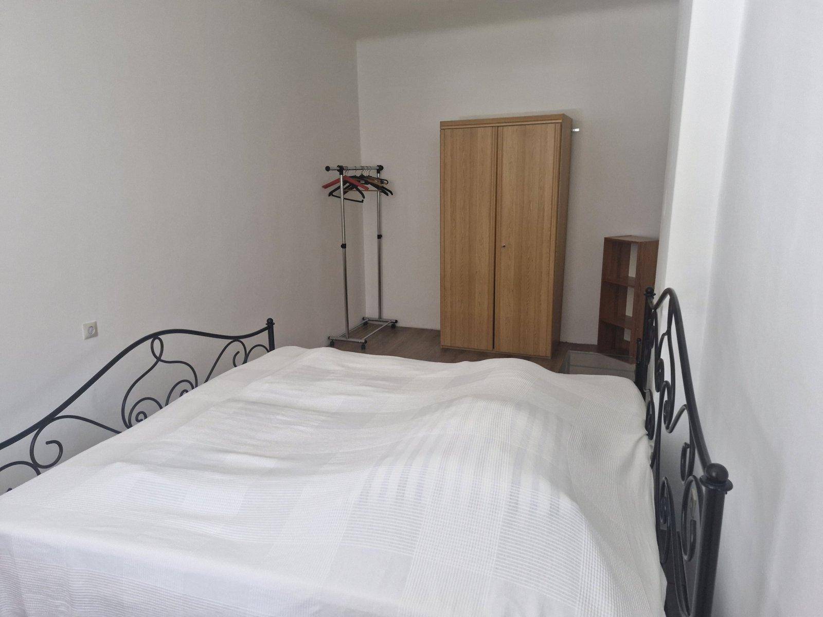 Schlafzimmer mit schmiedeeisernem Doppelbett, Kleiderschrank und weiß gestrichenen Wänden.