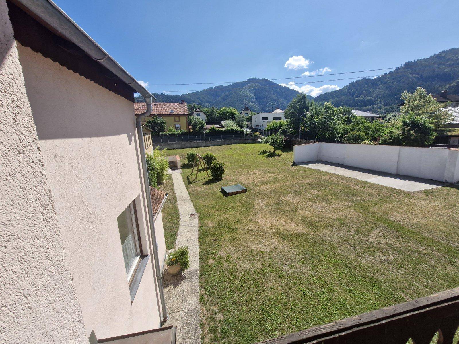 Panoramablick vom Balkon auf den weitläufigen Garten und die umliegende Berglandschaft.