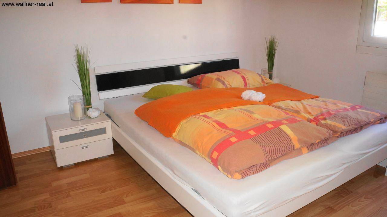 Gemütliches Schlafzimmer mit Doppelbett, Holzfußboden und Nachttisch.