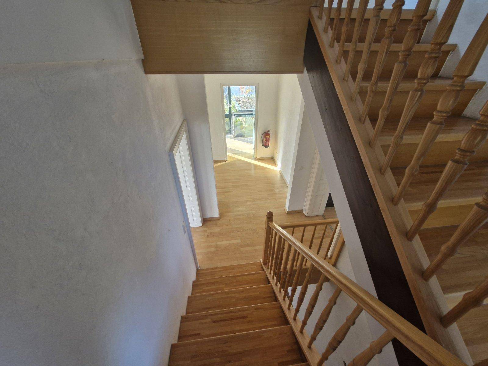 Blick von oben auf die Holztreppe und den hellen Flur mit Parkettboden.