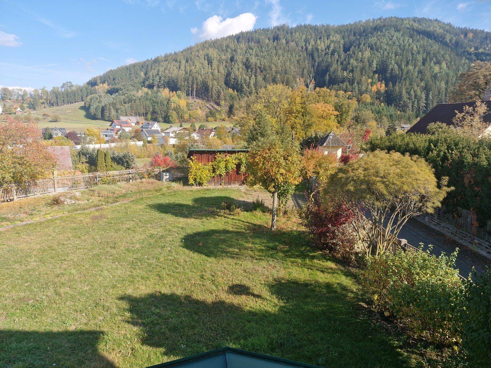 Weitblick über den gepflegten Garten mit Bäumen und die umliegende Berglandschaft.
